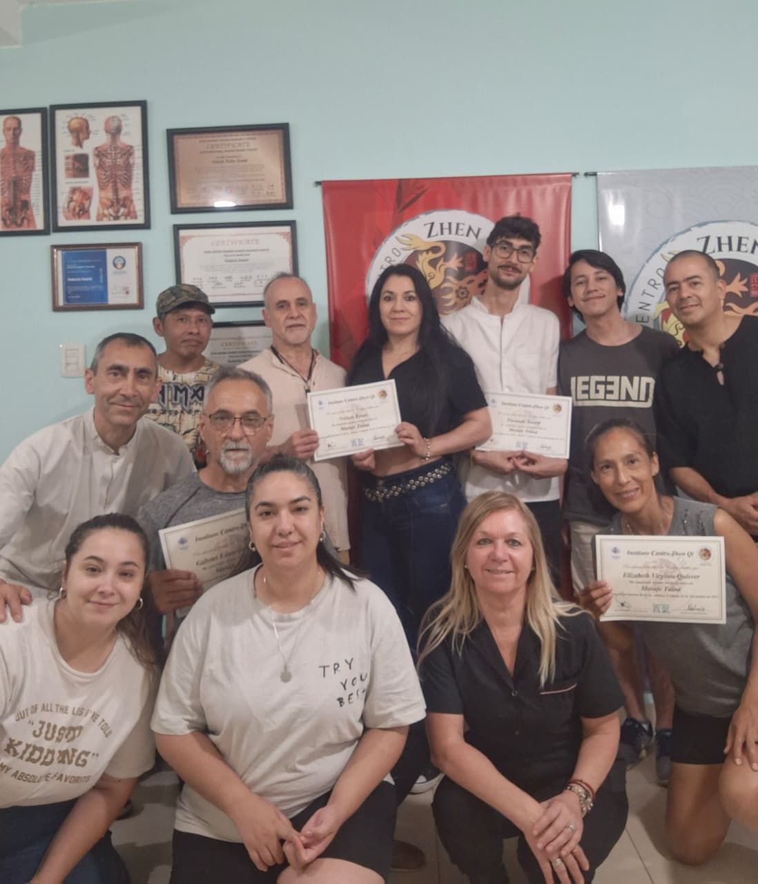 Grupo de personas con certificados, sonriendo. Algunos con diplomas en una sala bien iluminada.