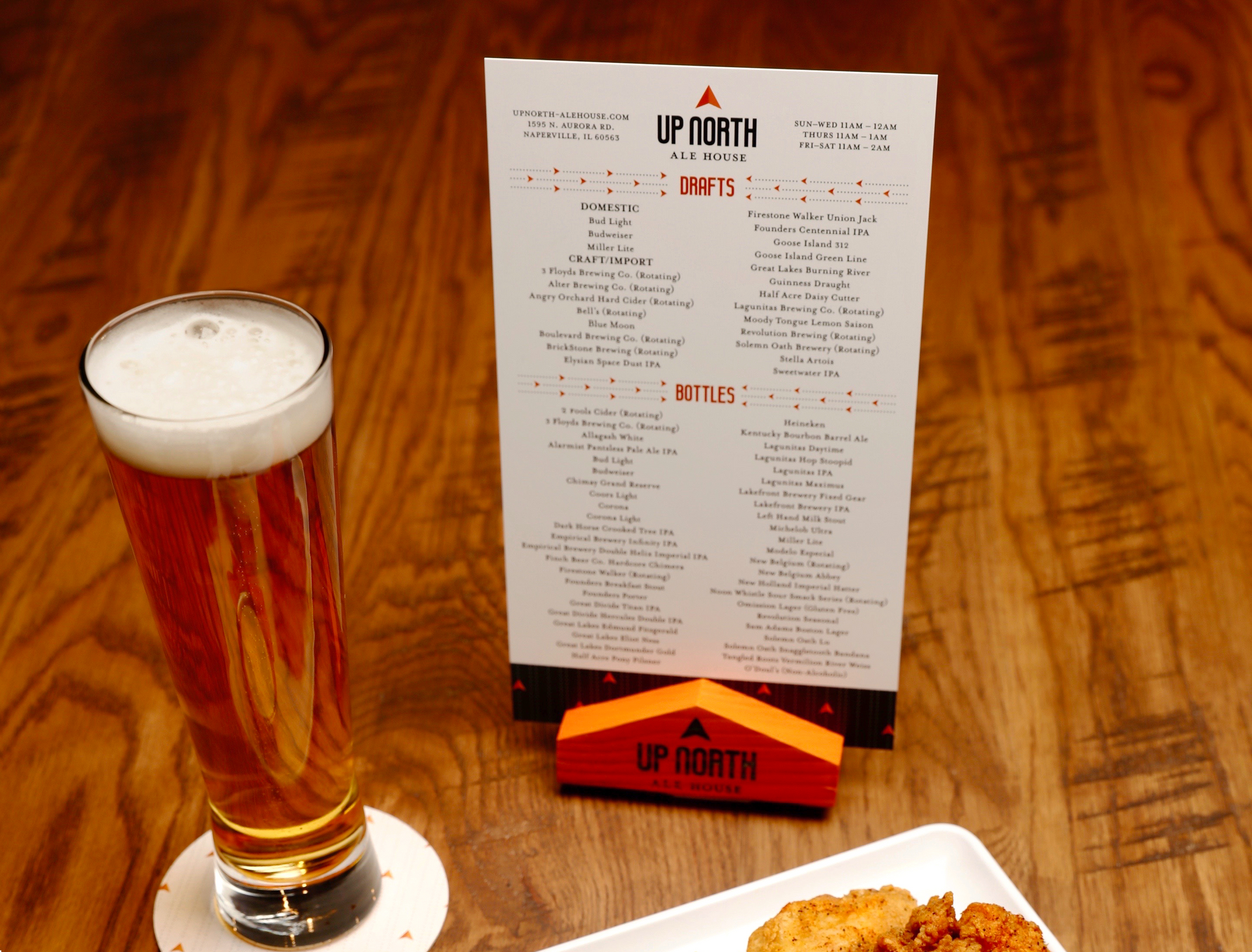 A glass of beer sits next to a up north menu