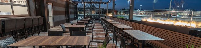 A row of tables and chairs in a restaurant with a fire pit in the background.