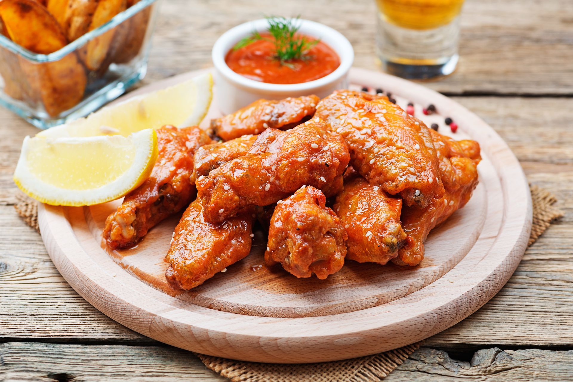 A wooden cutting board topped with chicken wings and french fries.