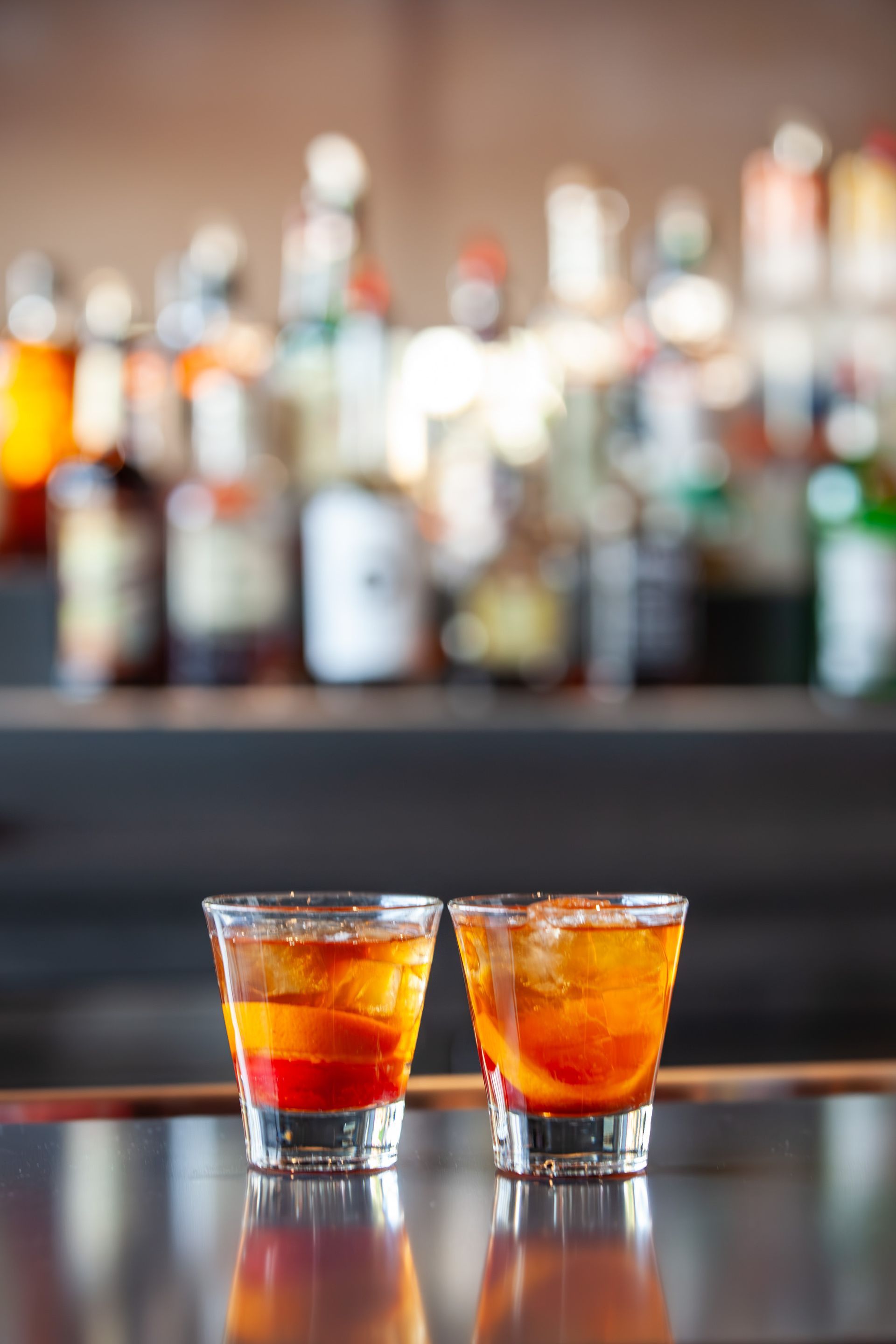 Two shot glasses of alcohol are sitting on a bar counter.