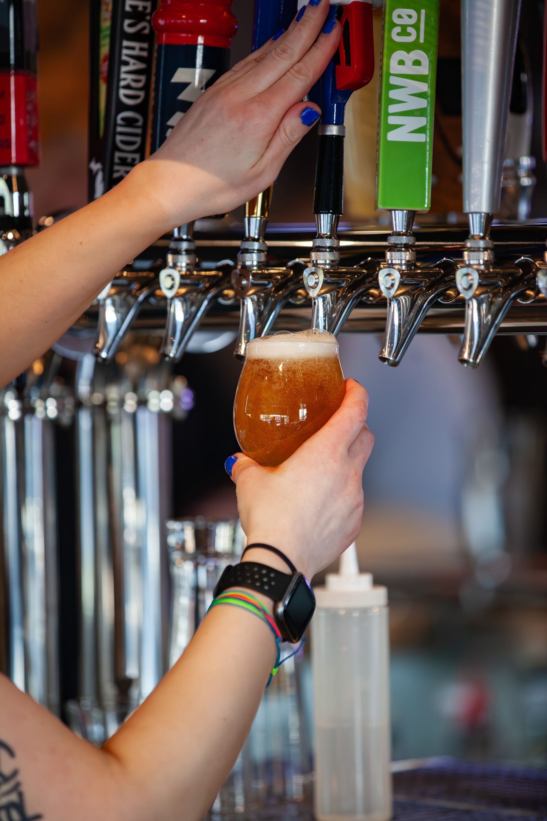 A woman is pouring beer from a tap into a glass.