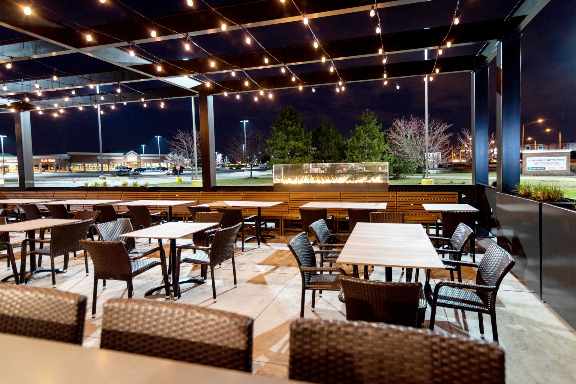 A restaurant with tables and chairs is lit up at night.