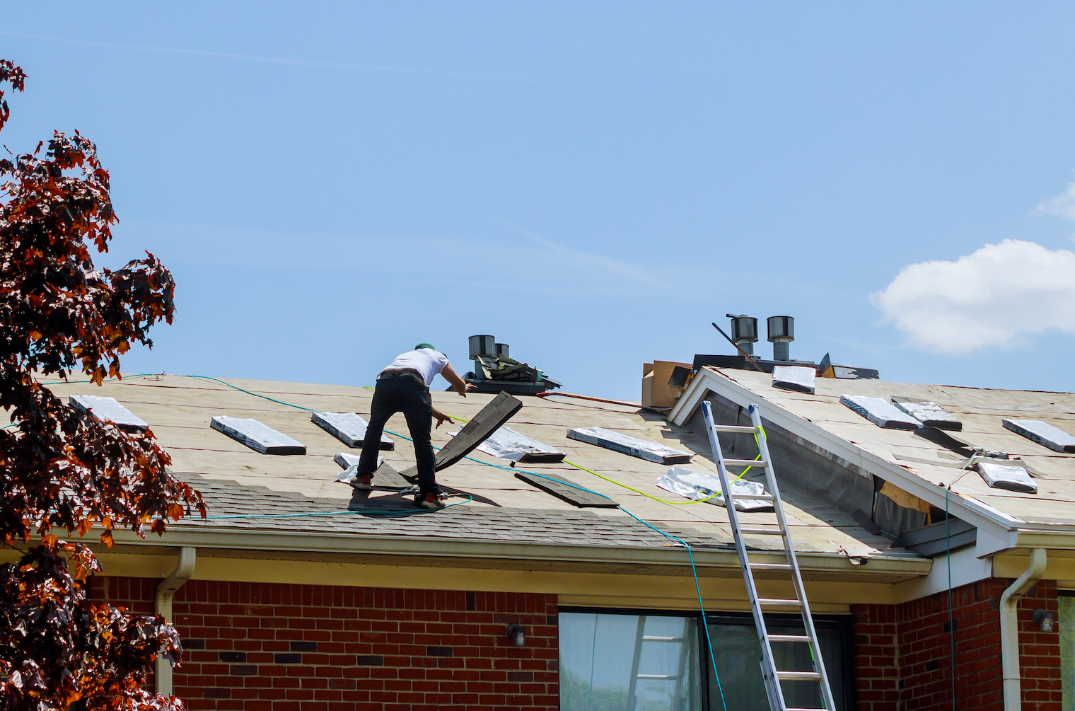 Workers replacing an existing roof with new shingles