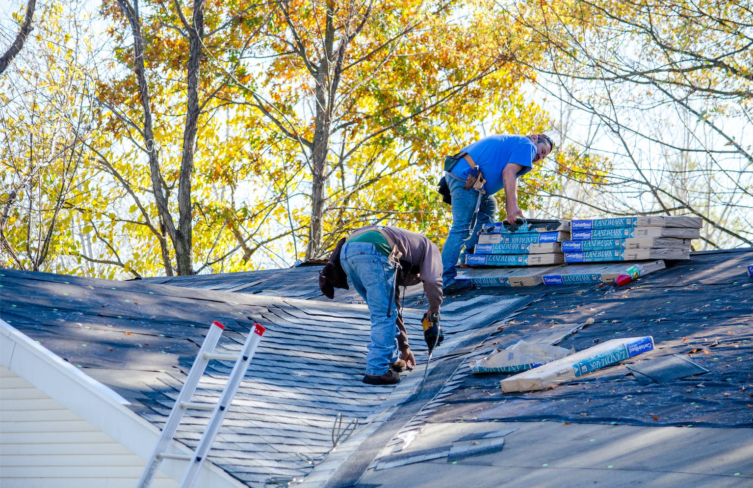 Workers on a roof replacing shingles