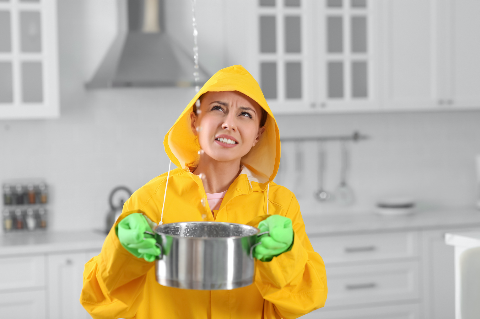 Young woman holding a pot catching dripping water from roof leak