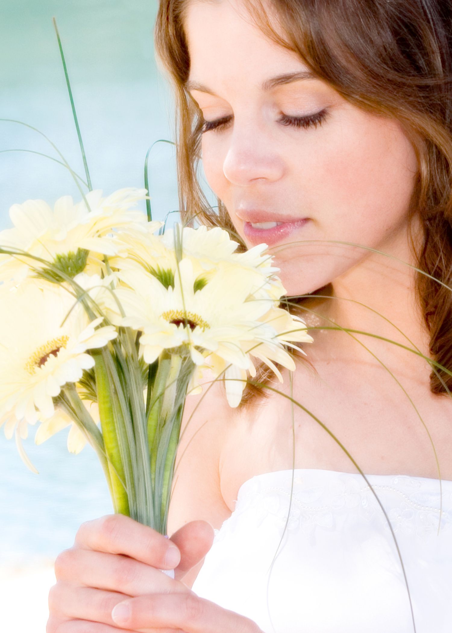 Woman smelling white daisies. Eyes closed, outdoors.