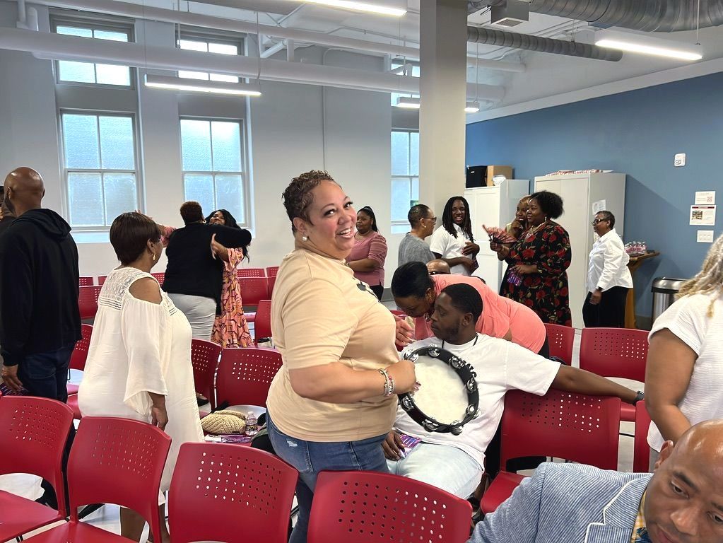 a woman holding a tambourine standing in a room of people