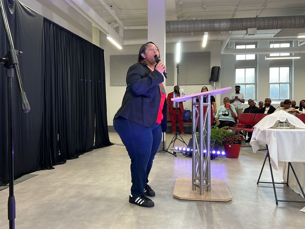 A woman is standing at a podium speaking into a microphone.