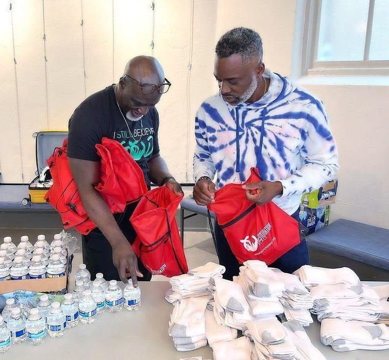A man in a tie dye shirt is looking at a red bag