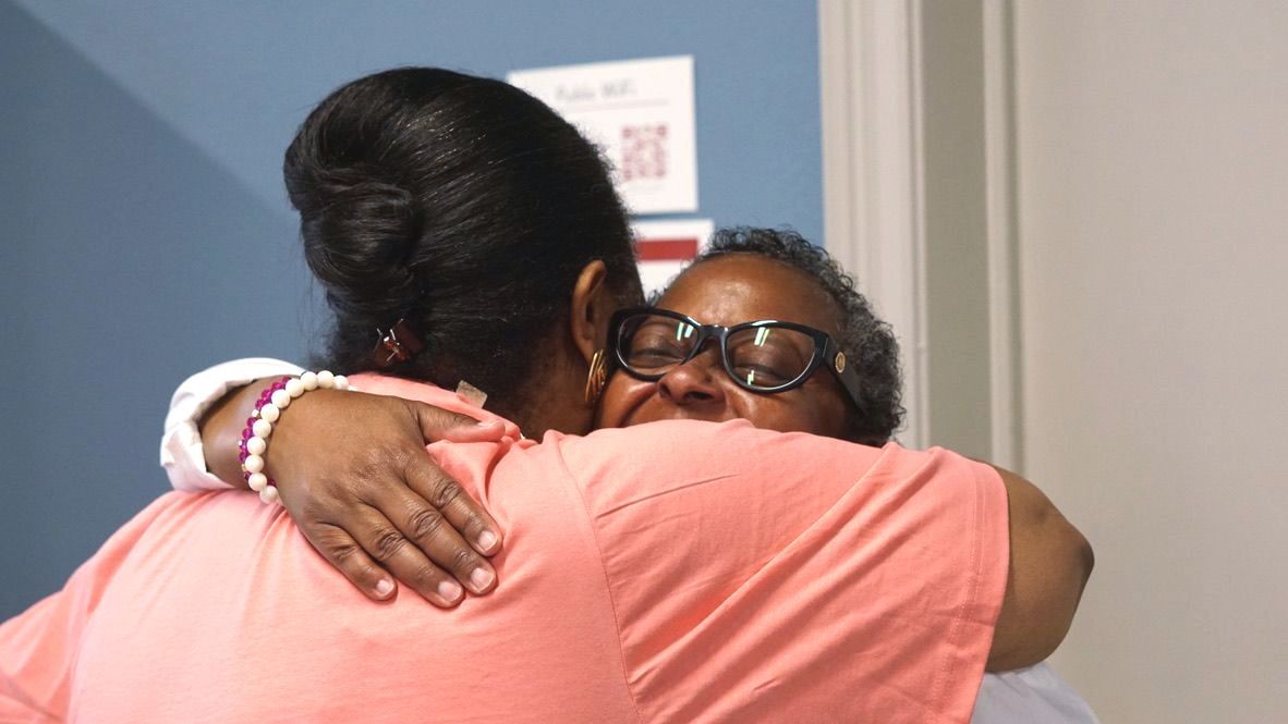 two women are hugging each other in a room .