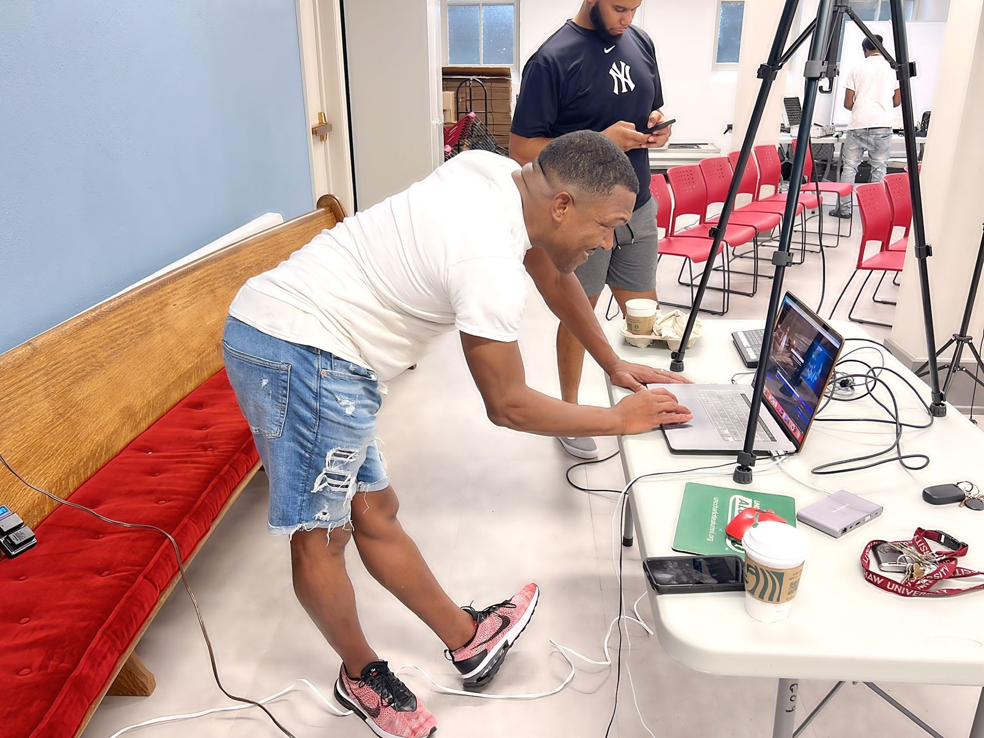 A man is using a laptop while another man is using a cell phone