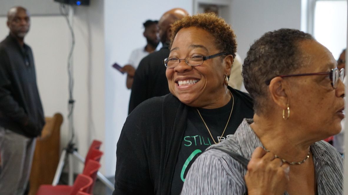 two women are standing next to each other in a room and smiling .