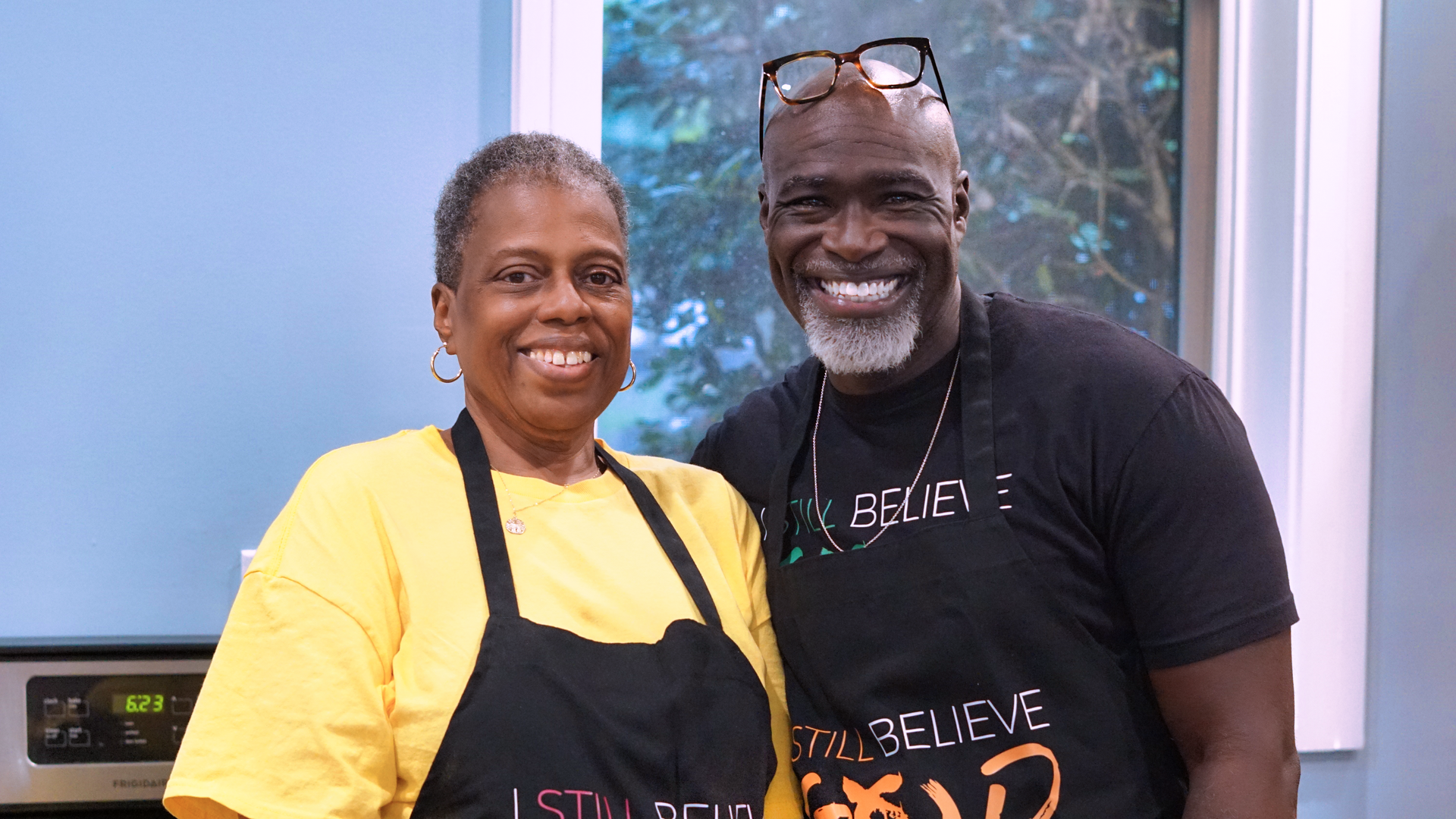 a man and a woman are posing for a picture in a kitchen .
