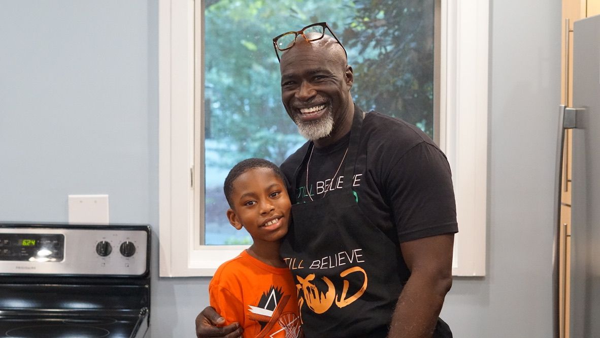 a man and a boy are posing for a picture in a kitchen .