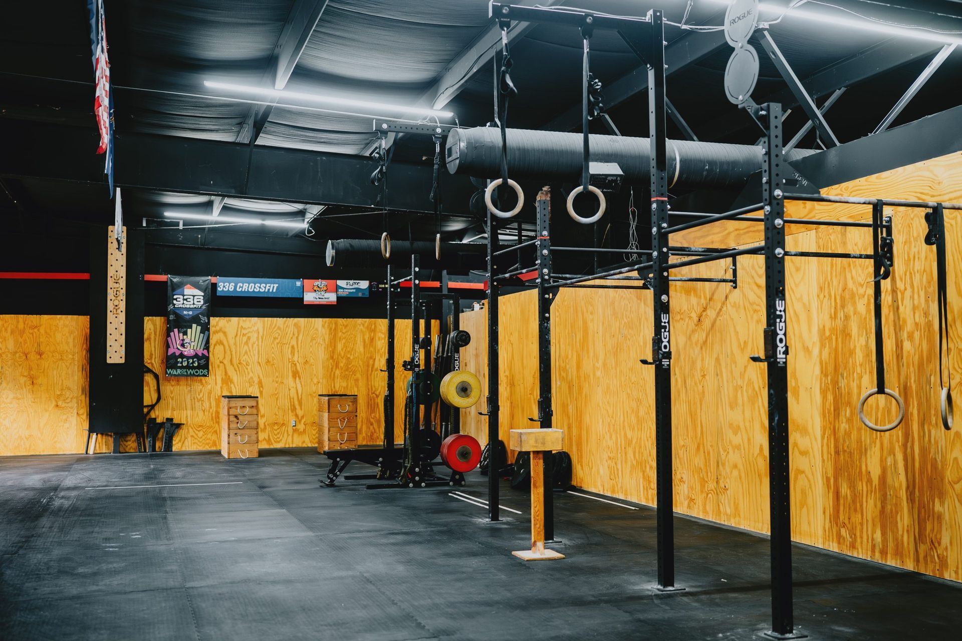 People exercising in a CrossFit gym, reaching overhead during a group workout.