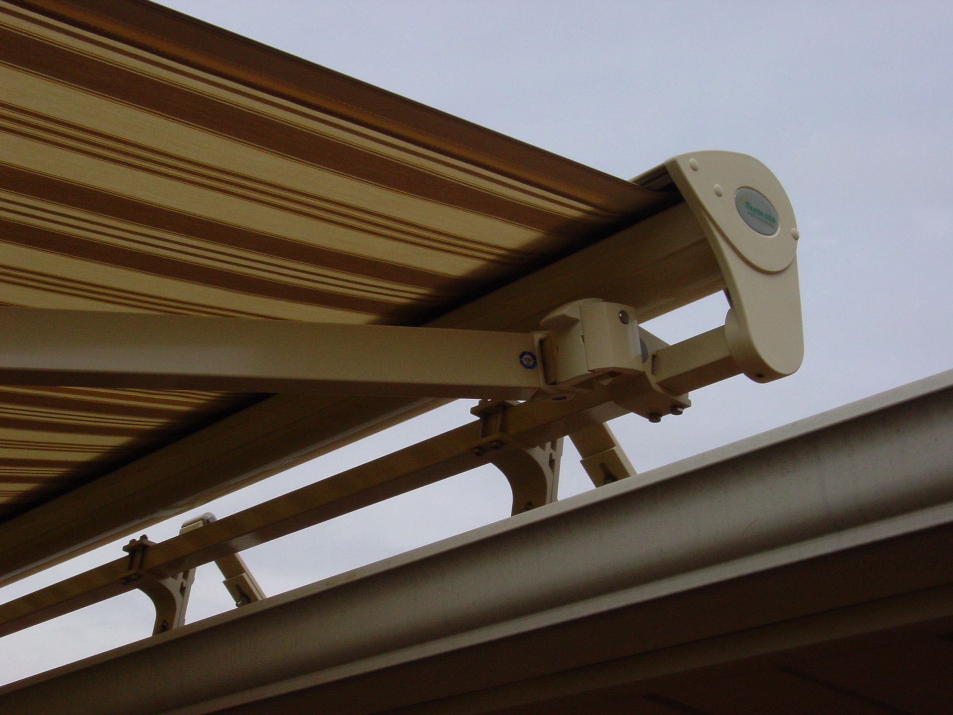 Beige and brown striped retractable awning attached to a building, partially extended.