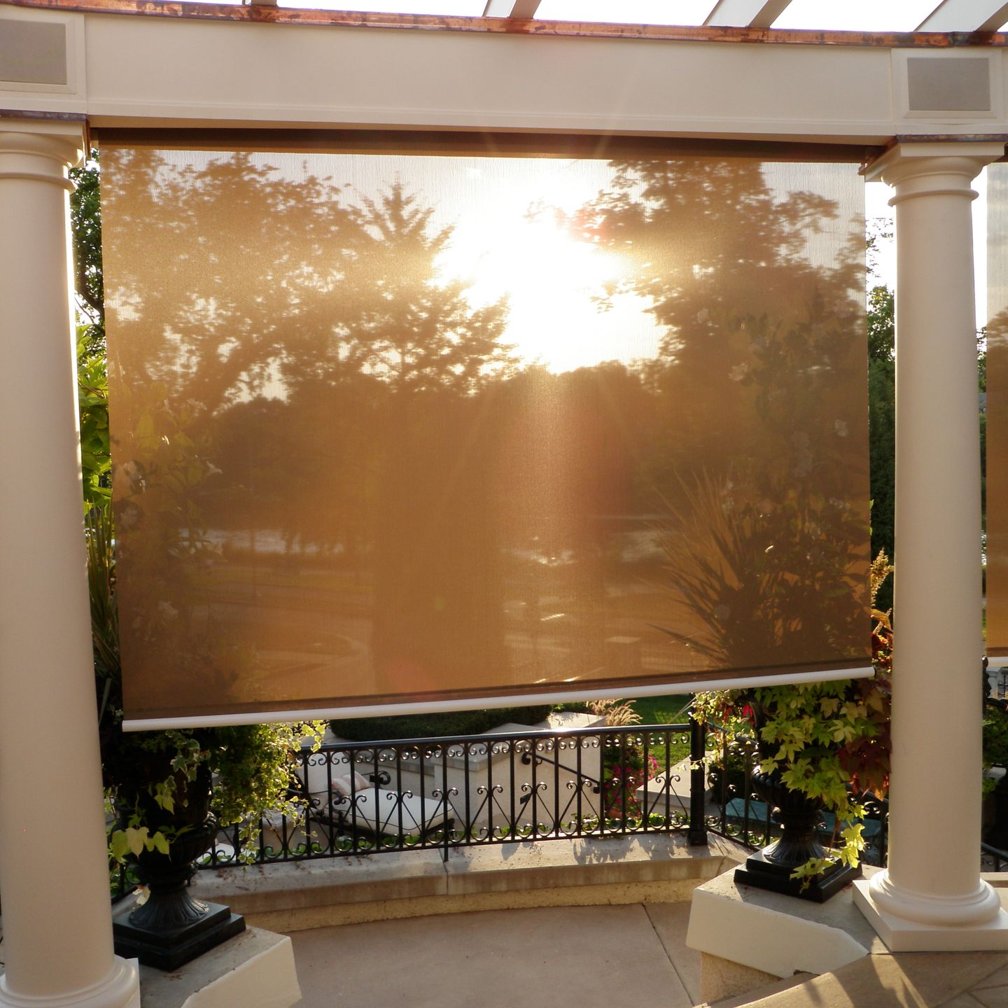 Exterior patio with sun filtering through a brown shade, creating a warm glow.