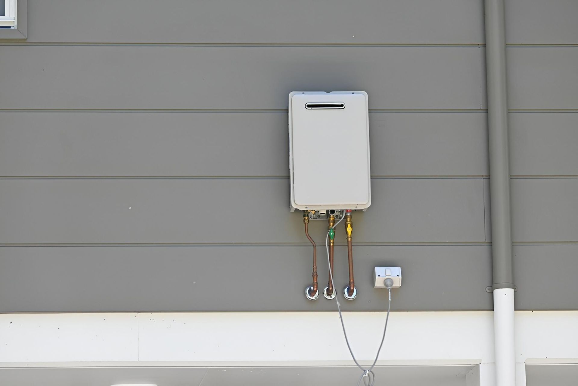 A White Water Heater is Attached to the Side of a Building — Vision Plumbing Queensland in Pimlico, QLD