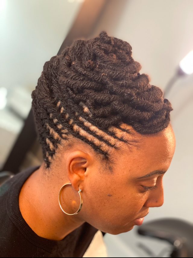 A close up of a woman with dreadlocks looking at the camera.