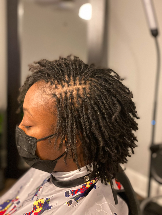 A woman with dreadlocks is smiling and wearing a black shirt