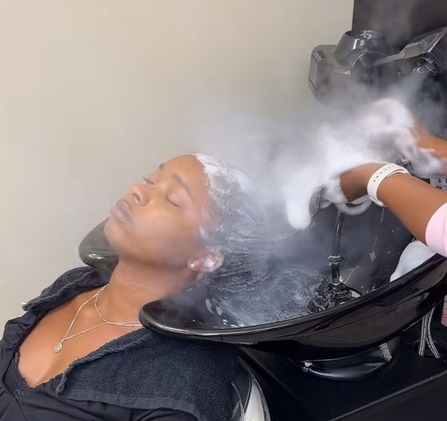 A woman is getting her hair washed in a sink at a salon.