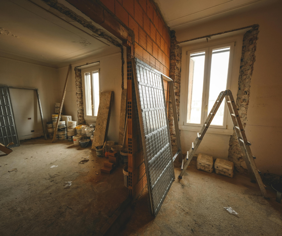 Interior room under construction, with drywall compound, ladder, and building materials.