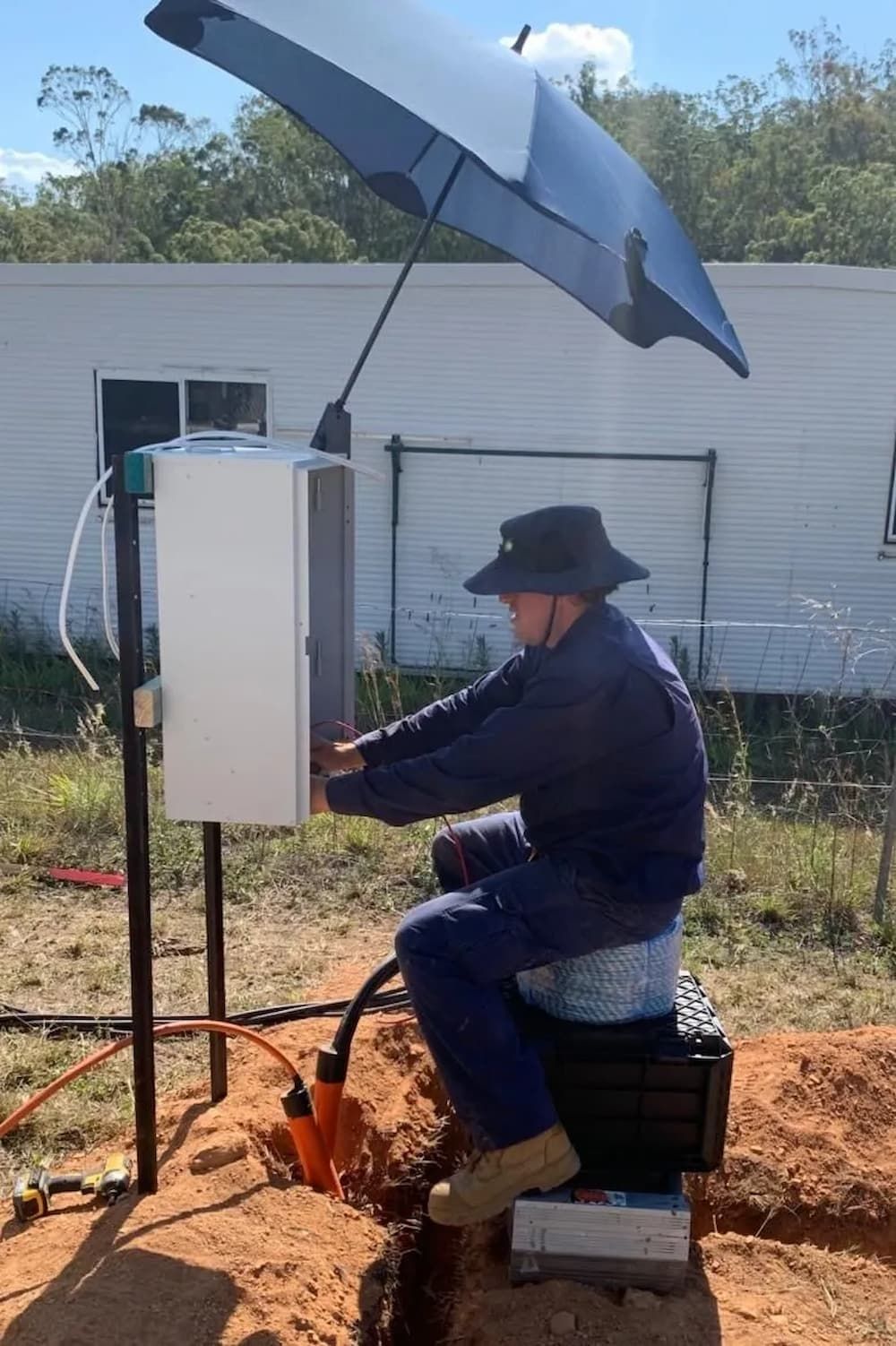 A Man is Sitting on a Box Under an Umbrella — Central Electrical Group in Gladstone Central, QLD
