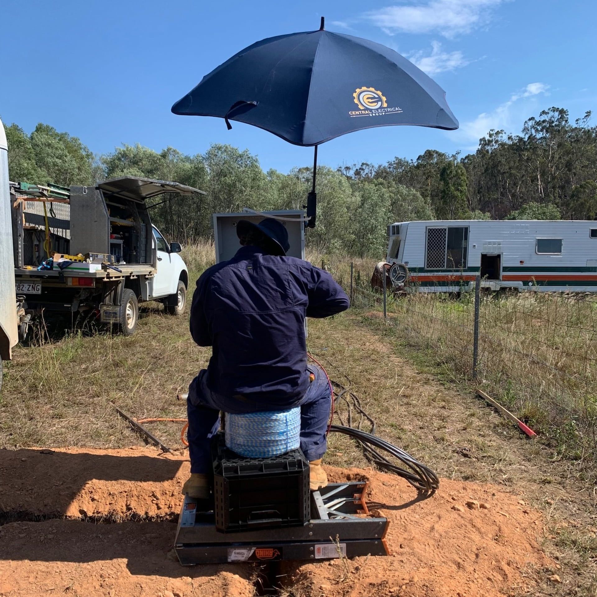 A Man is Sitting Under an Umbrella in a Field — Central Electrical Group in Gladstone Central, QLD