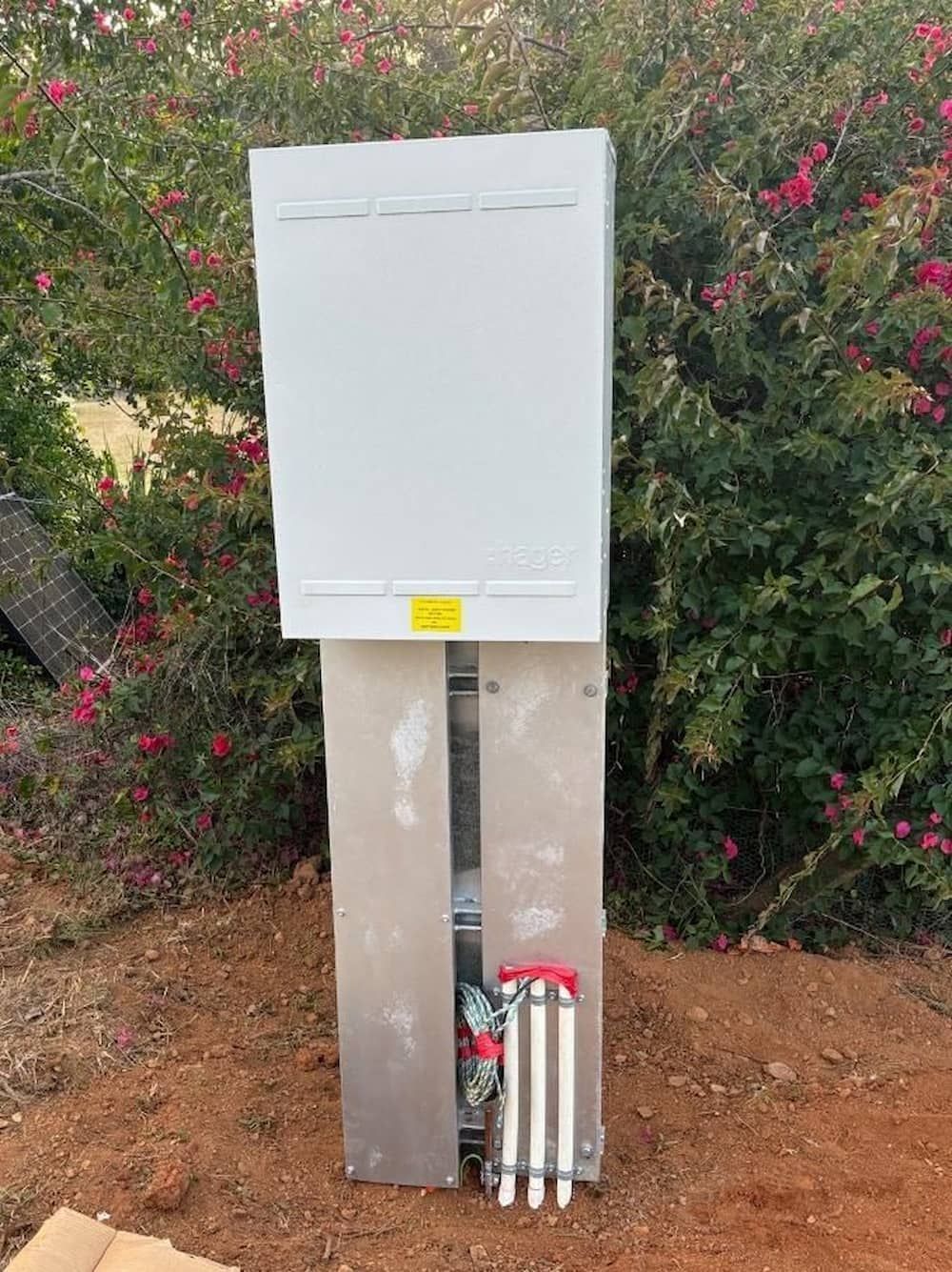 A White Box is Sitting in the Dirt Next to a Bush — Central Electrical Group in Gladstone Central, QLD