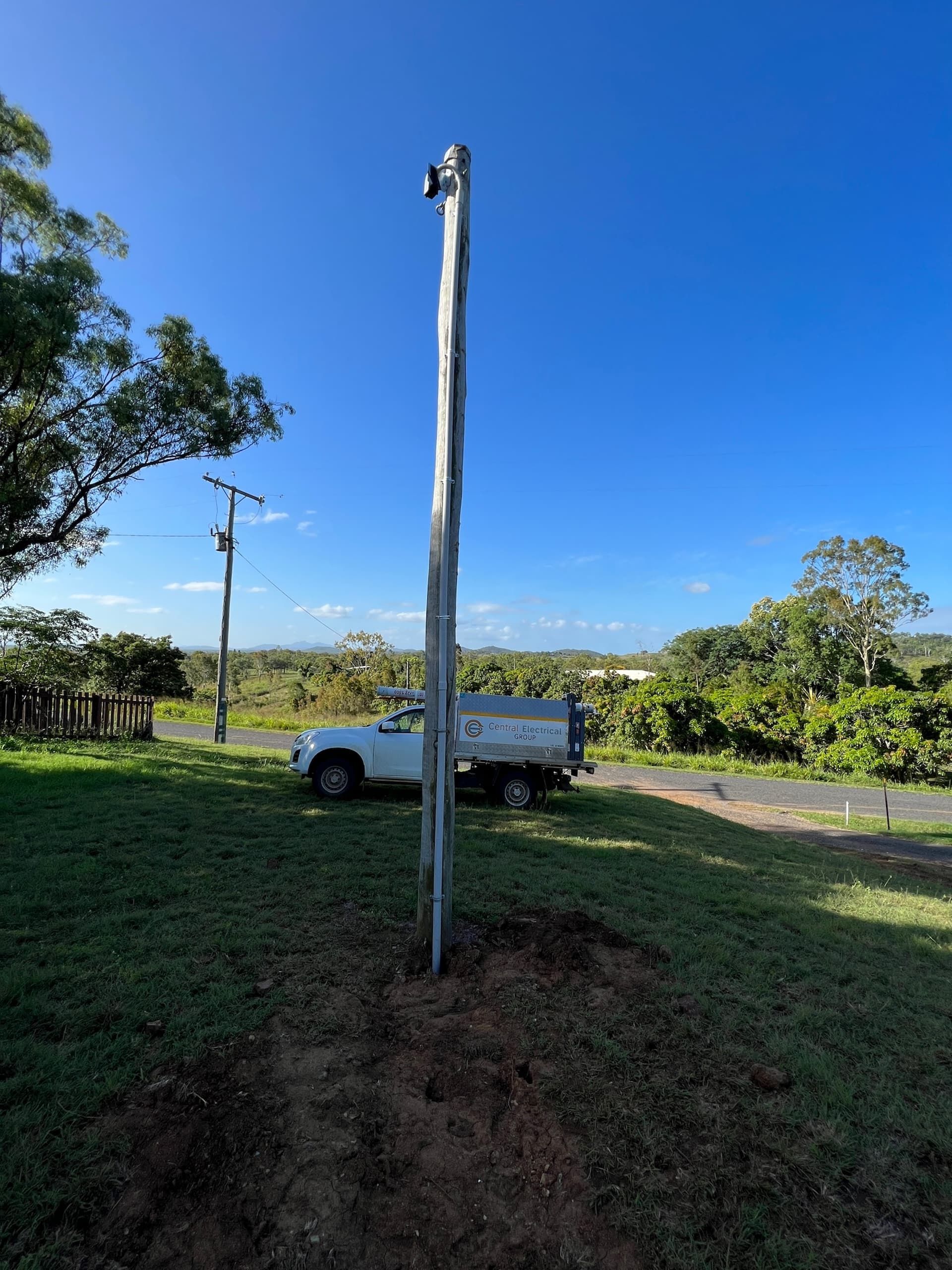 A White Truck is Parked in a Grassy Field Next to a Pole — Central Electrical Group in Gracemere, QLD