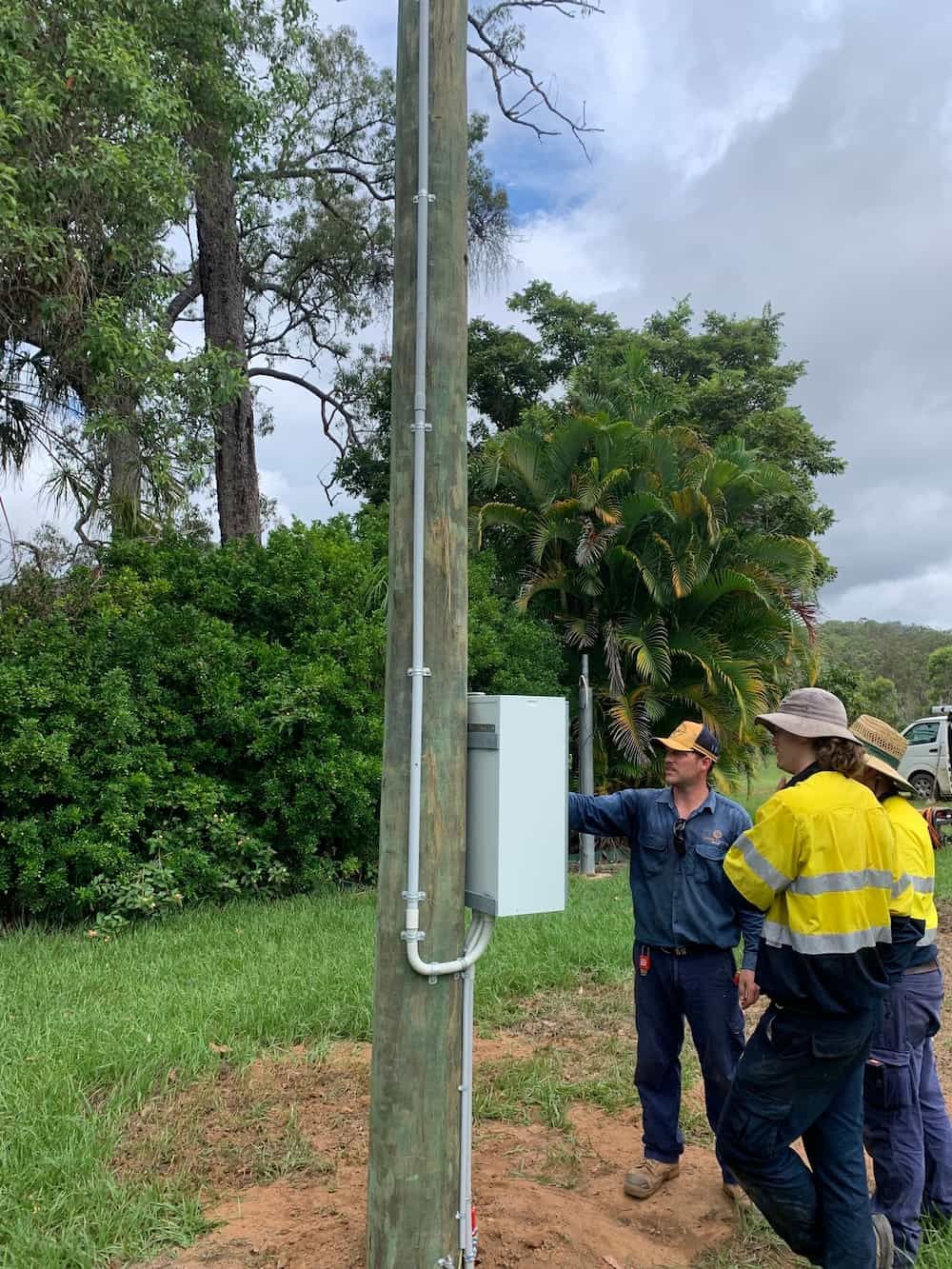 A Group of Men Are Standing Around a Pole in a Field — Central Electrical Group in Rockhampton, QLD