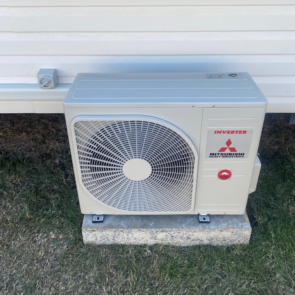 A Mitsubishi Air Conditioner is Sitting on Top of a Concrete Block — Central Electrical Group in Gladstone Central, QLD