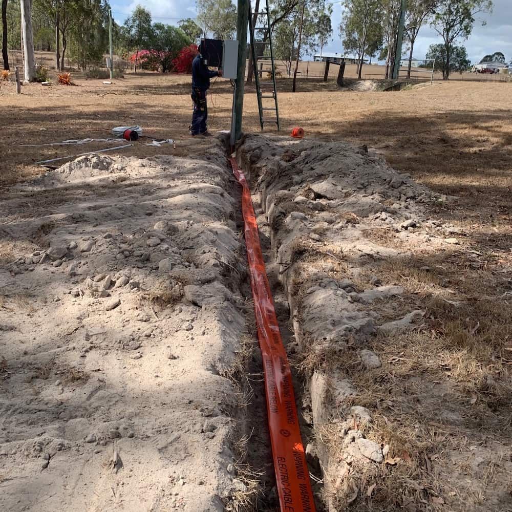 A Man is Working on a Pipe in the Dirt — Central Electrical Group in Rockhampton, QLD