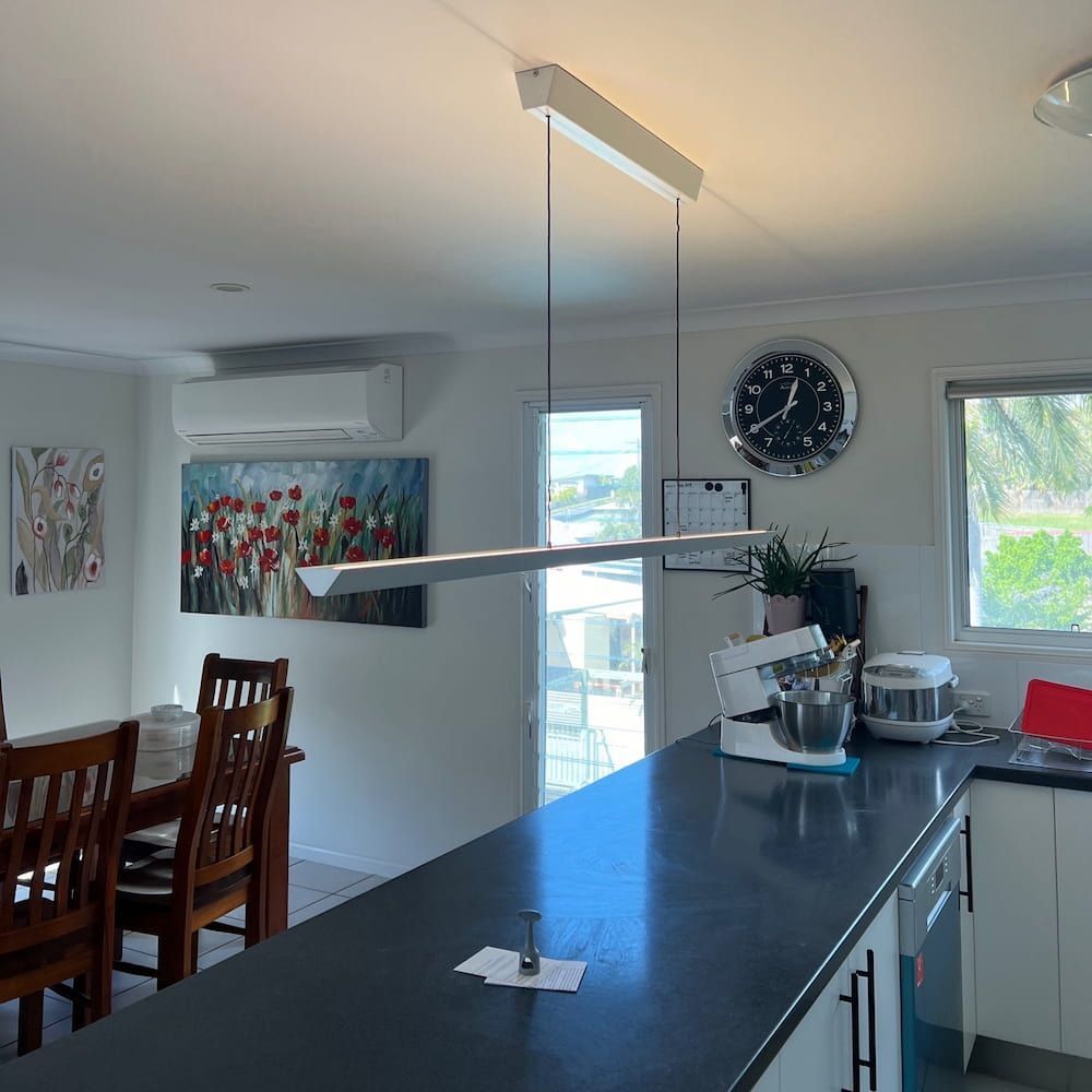 A Kitchen With a Large Island and a Clock on the Wall — Central Electrical Group in Rockhampton, QLD