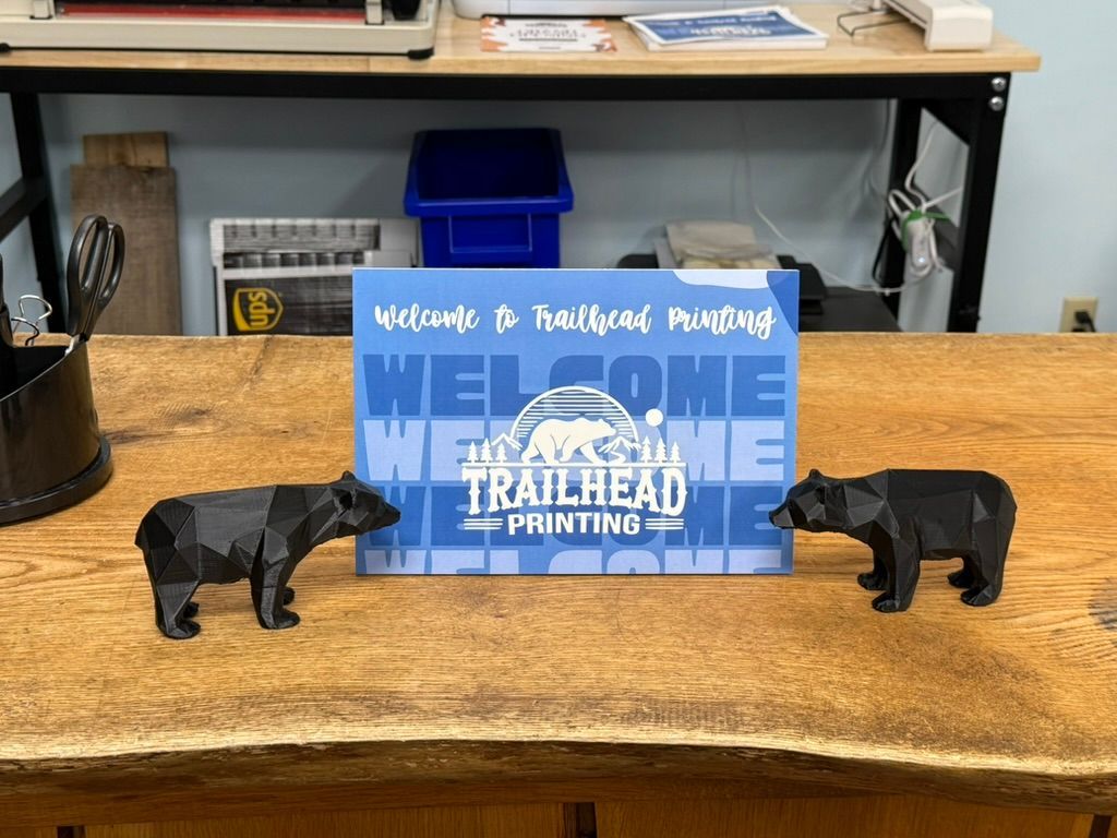 Two black bear figures flank a sign that reads 