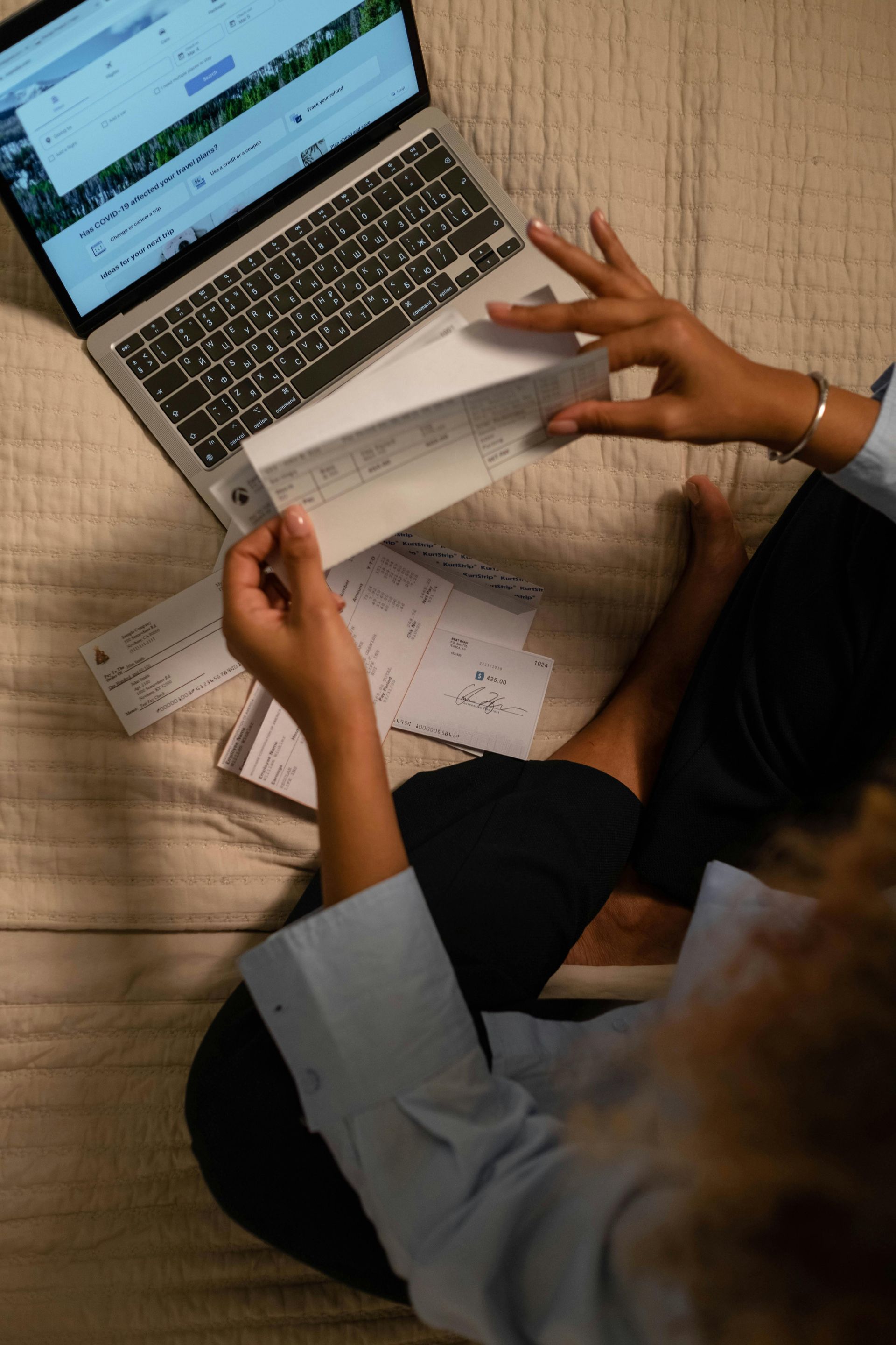 Person sitting with a laptop and papers, reviewing documents.