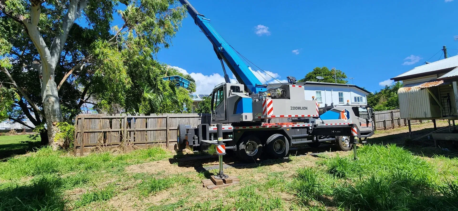A Blue and Gray Crane Truck Parked on a Grassy Yard — Presto's Cranes & Rigging NQ in Garbutt, QLD