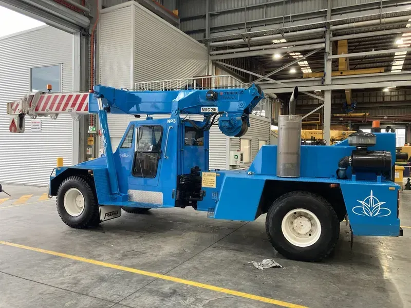 Blue Industrial Crane Truck With White Wheels in a Warehouse — Presto's Cranes & Rigging NQ in Garbutt, QLD