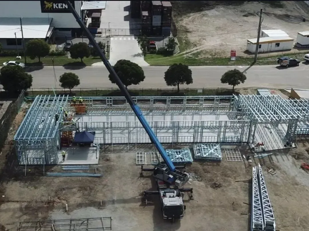 Construction Site With Crane Lifting Metal Framework — Presto's Cranes & Rigging NQ in Garbutt, QLD