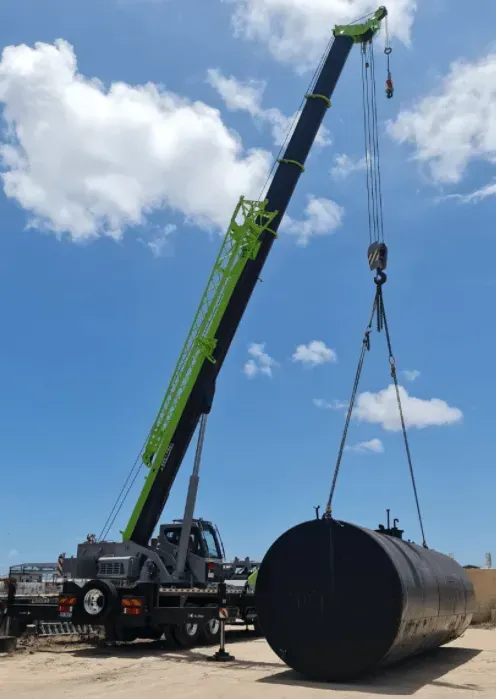 Crane Lifting a Large Black Cylindrical Tank Outdoors — Presto's Cranes & Rigging NQ in Garbutt, QLD