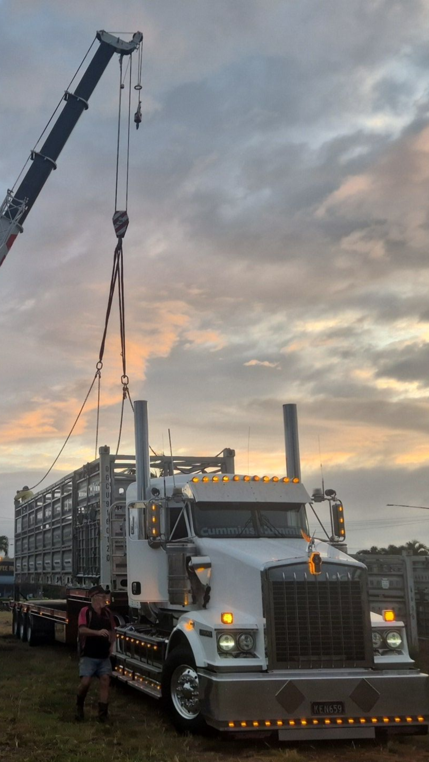 A White Semi-truck is Lifted by a Crane Outdoors With a Person Nearby — Presto's Cranes & Rigging NQ in Garbutt, QLD