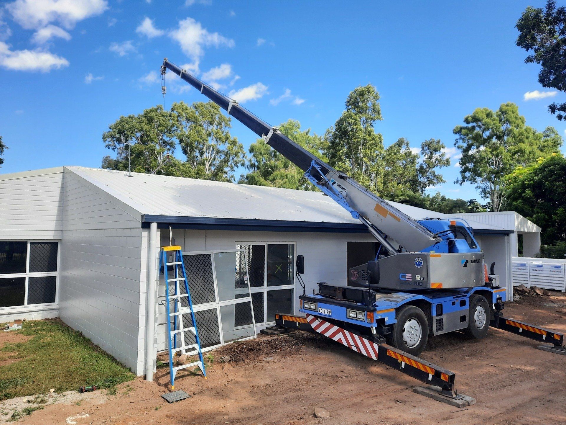 A Blue Crane Extending Over a Building for Construction Work — Presto's Cranes & Rigging NQ in Garbutt, QLD
