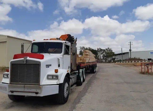 White Semi-truck Carrying Lumber on a Sunny Day — Presto's Cranes & Rigging NQ in Garbutt, QLD