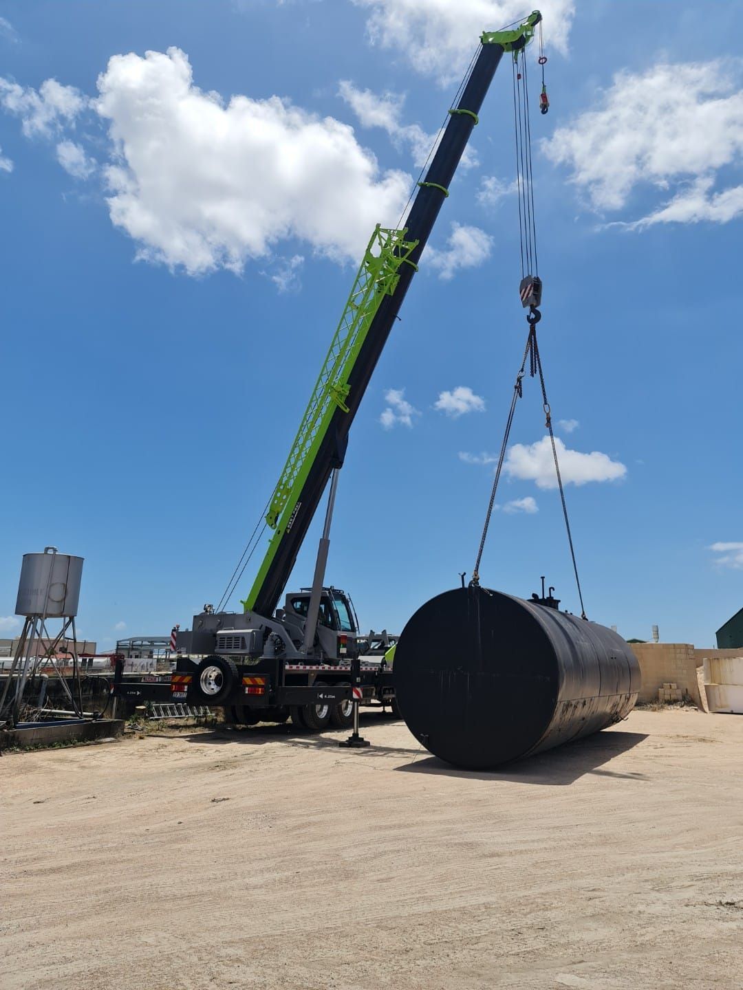 Crane Lifting a Large Black Cylindrical Tank — Presto's Cranes & Rigging NQ in Garbutt, QLD