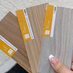 Una persona sostiene un abanico con muestras de madera en su mano.