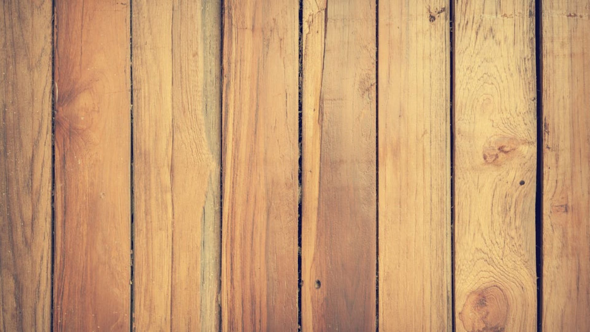 Un primer plano de un piso de madera con una valla de madera al fondo.