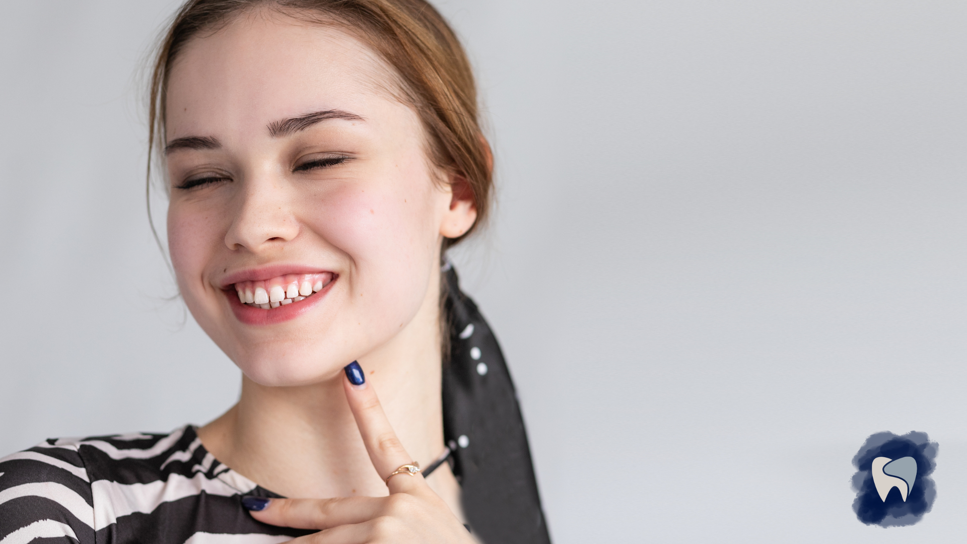 A woman is smiling and pointing at her teeth.