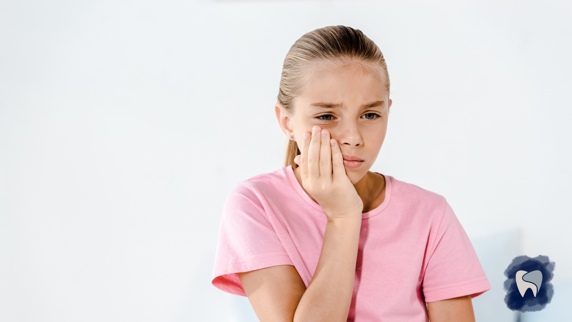 A young girl is holding her face in pain because of a toothache.