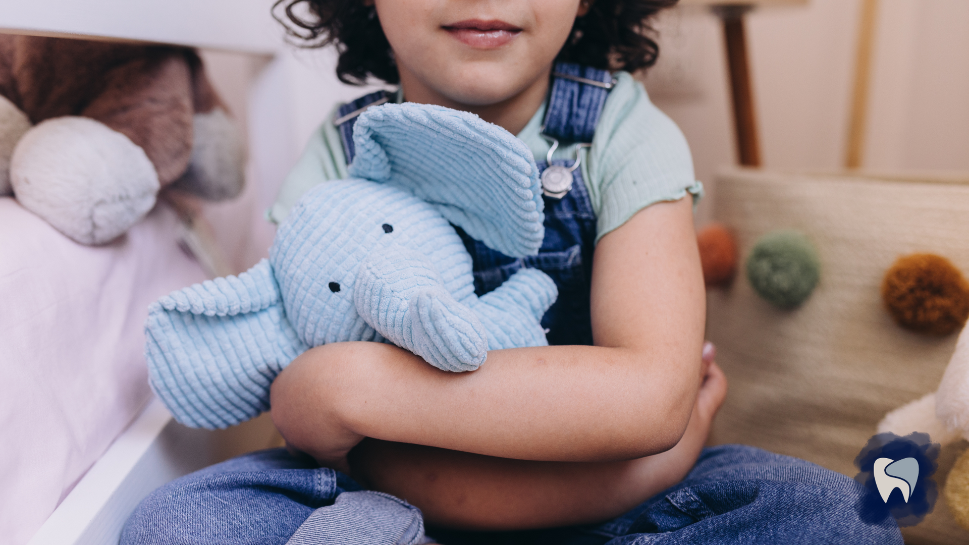 A little girl is sitting on the floor holding a stuffed elephant.